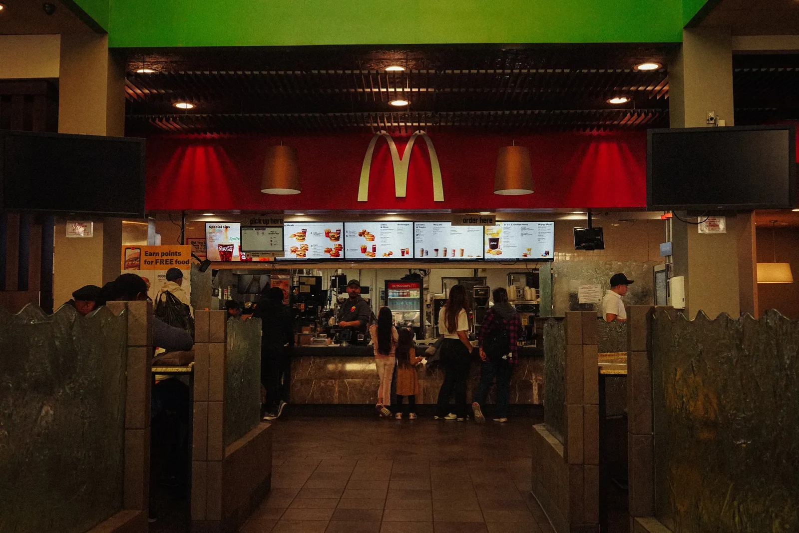 A bustling scene at a McDonald's restaurant counter with customers and staff in an indoor setting.