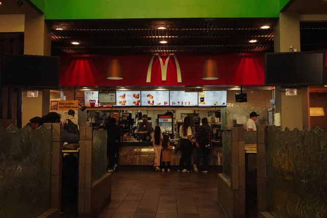 A bustling scene at a McDonald's restaurant counter with customers and staff in an indoor setting. Franchisemodellen: krav, kostnader och ansvar